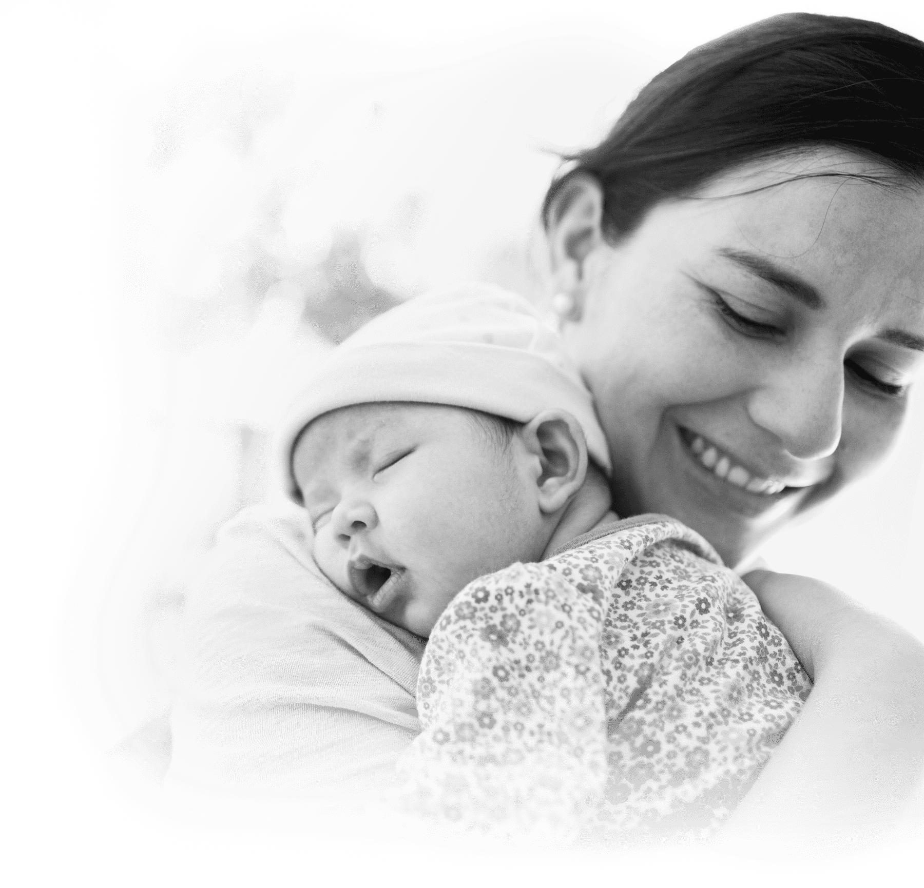 Woman smiling holding sleeping baby.